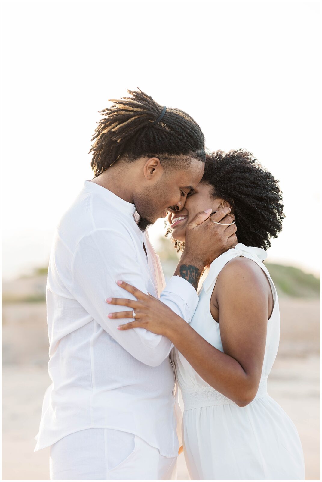 Romantic moment of the couple holding each other close with their foreheads touching and smiling softly, captured at golden hour during their Ponte Vedra Beach engagement session.