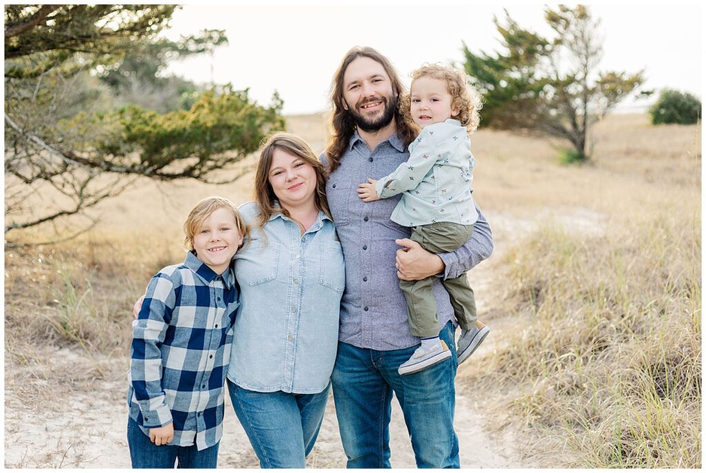 Family standing together during a Fort Clinch State Park family session with soft winter light and coastal scenery