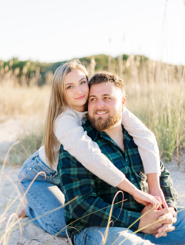 Couple embracing in golden light during Fort Clinch engagement session surrounded by sea oats and coastal dunes