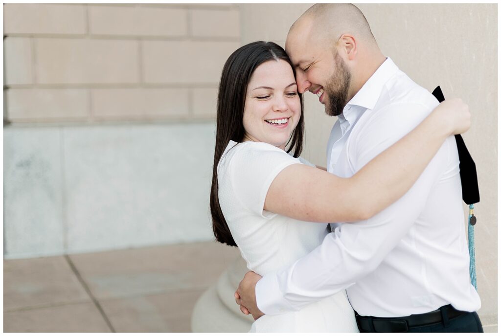 Sweet and joyful close-up of a Jacksonville University doctoral graduate sharing an embrace with her fiancé, both smiling with their foreheads together during their celebratory graduation photo session.