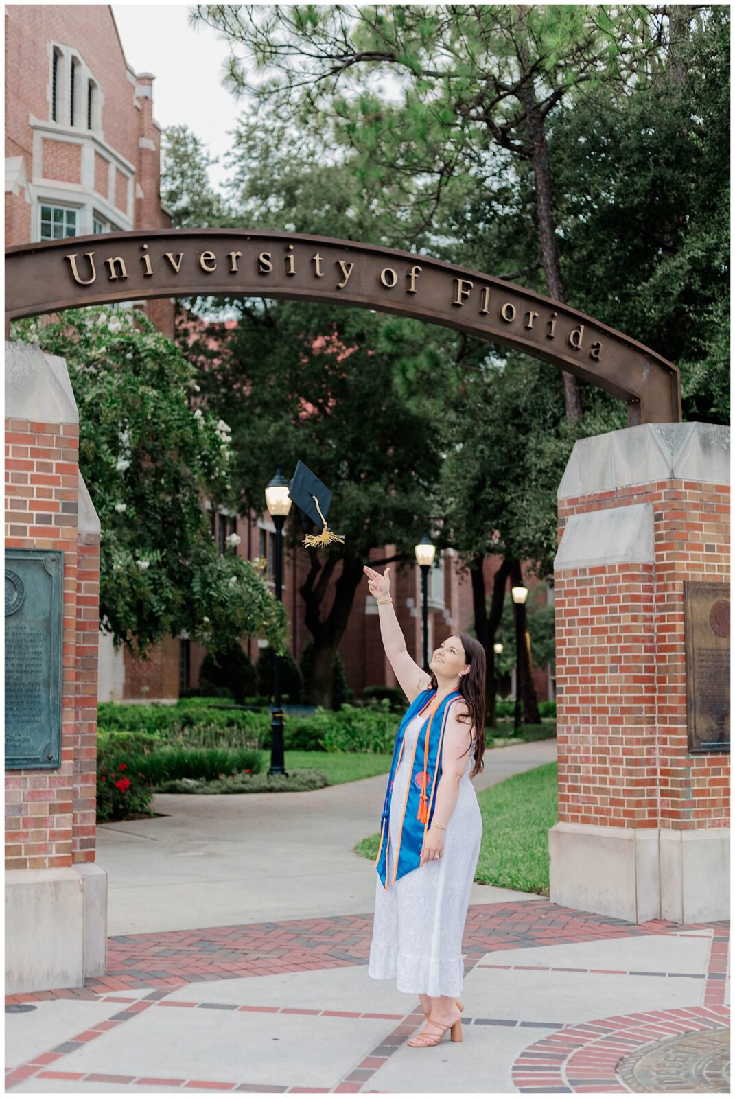University of Florida graduate celebrating during a UF grad session beneath the campus entrance arch