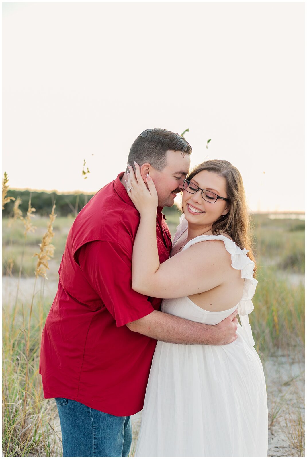 A quiet moment shared in the dunes as the couple embrace among sea oats and soft evening light during their Fort Clinch State Park engagement session.