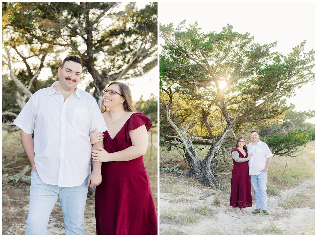 Engaged couple standing together beneath a large, windswept tree with sandy ground and tall grass at Fort Clinch State Park