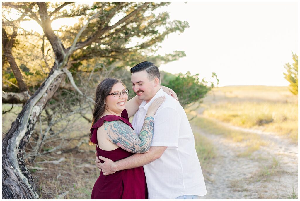 Close-up portrait of an engaged couple embracing beneath coastal trees with soft evening light at Fort Clinch State Park