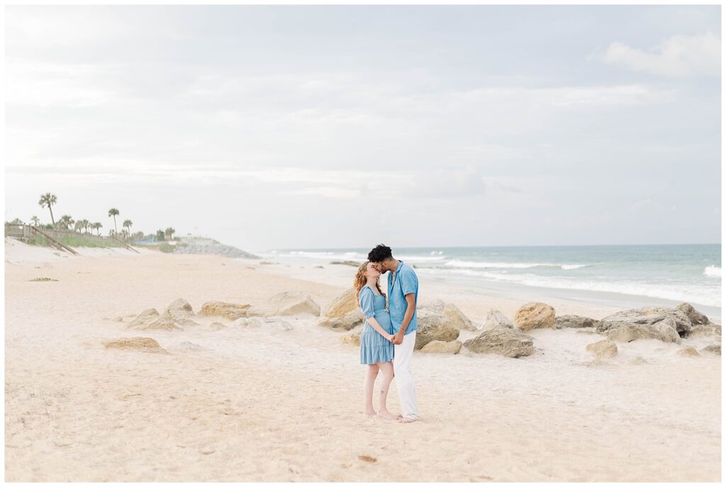 Romantic St. Augustine Beach maternity session with expecting parents framed by coastal rocks and soft light