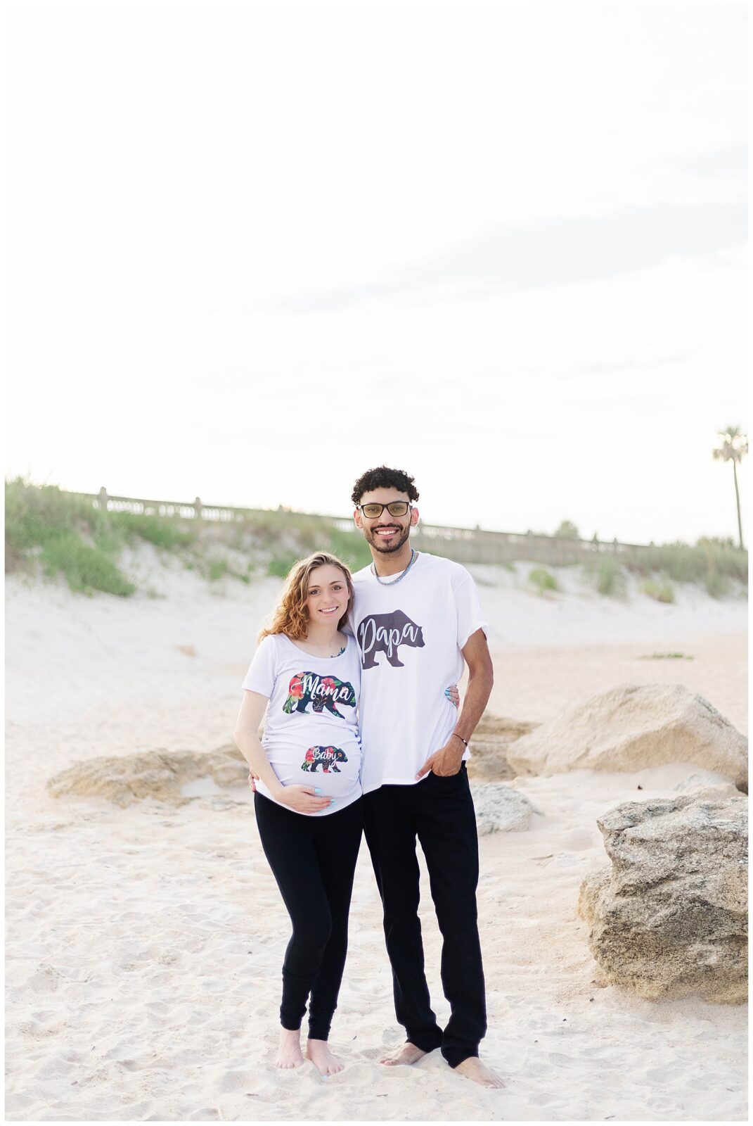 Casual St. Augustine Beach maternity photos of first-time parents wearing Mama and Papa shirts by the shoreline