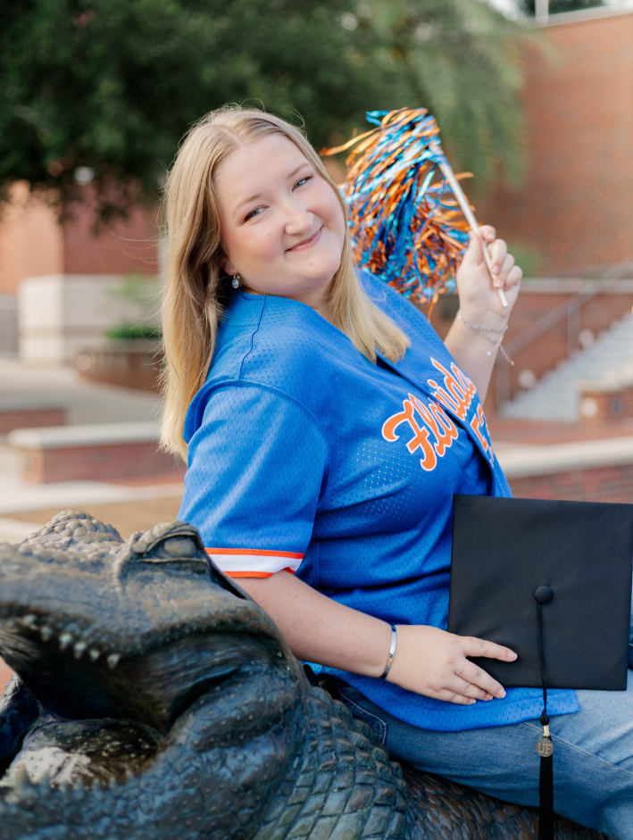 Graduate celebrating her University of Florida grad session with blue and orange spirit at the Gator statue on campus.