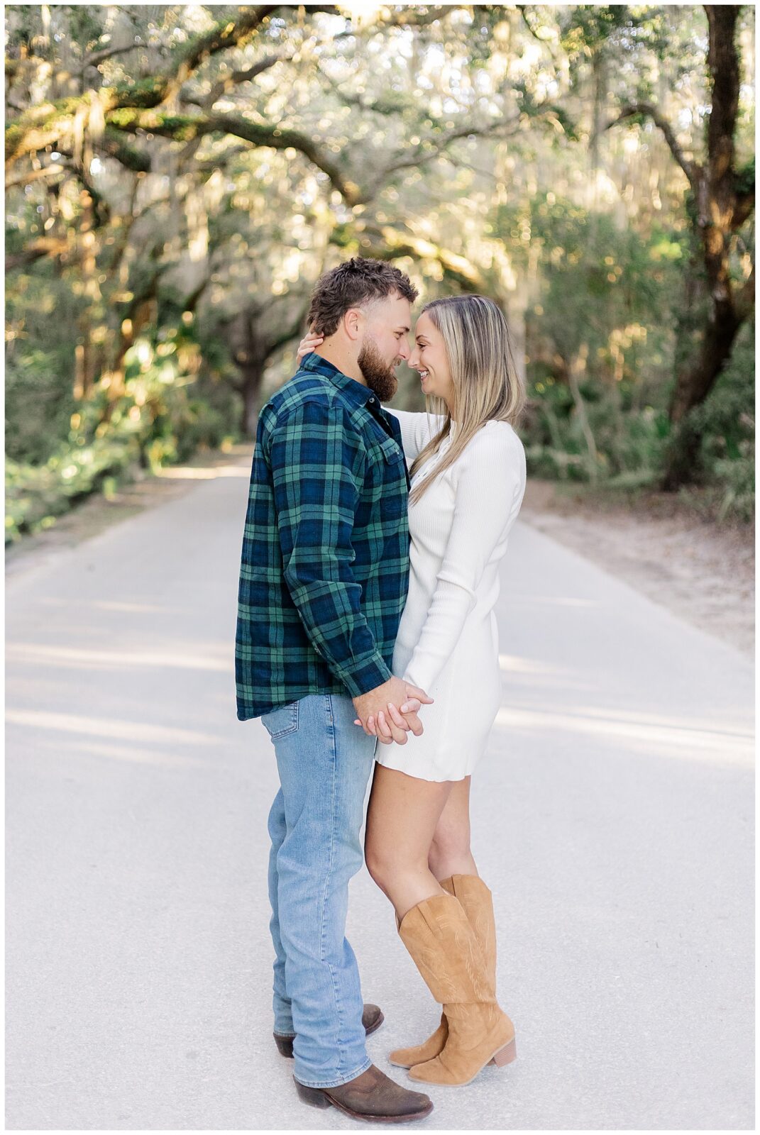 Fernandina Beach Engagement Session Romantic portrait of the pair standing face to face under arching oak branches with soft filtered light.
