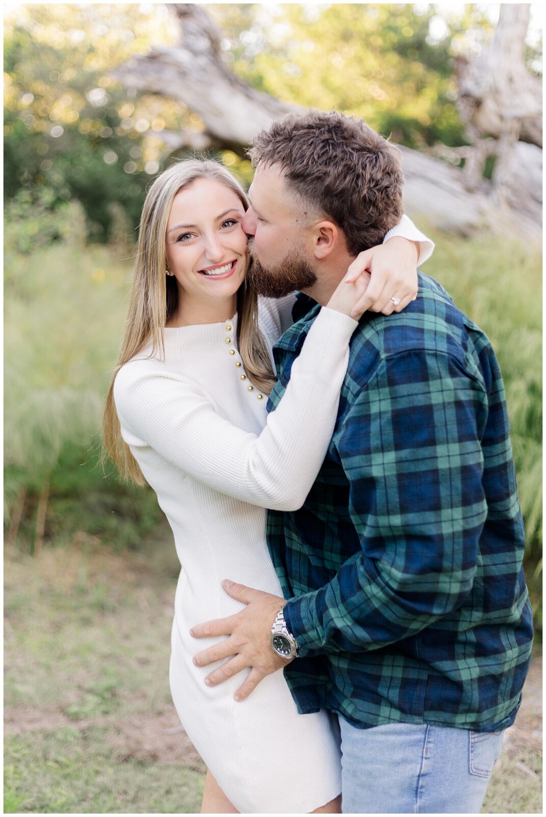 Couple embracing beneath a large driftwood tree at Fort Clinch State Park during their engagement session in Fernandina Beach.